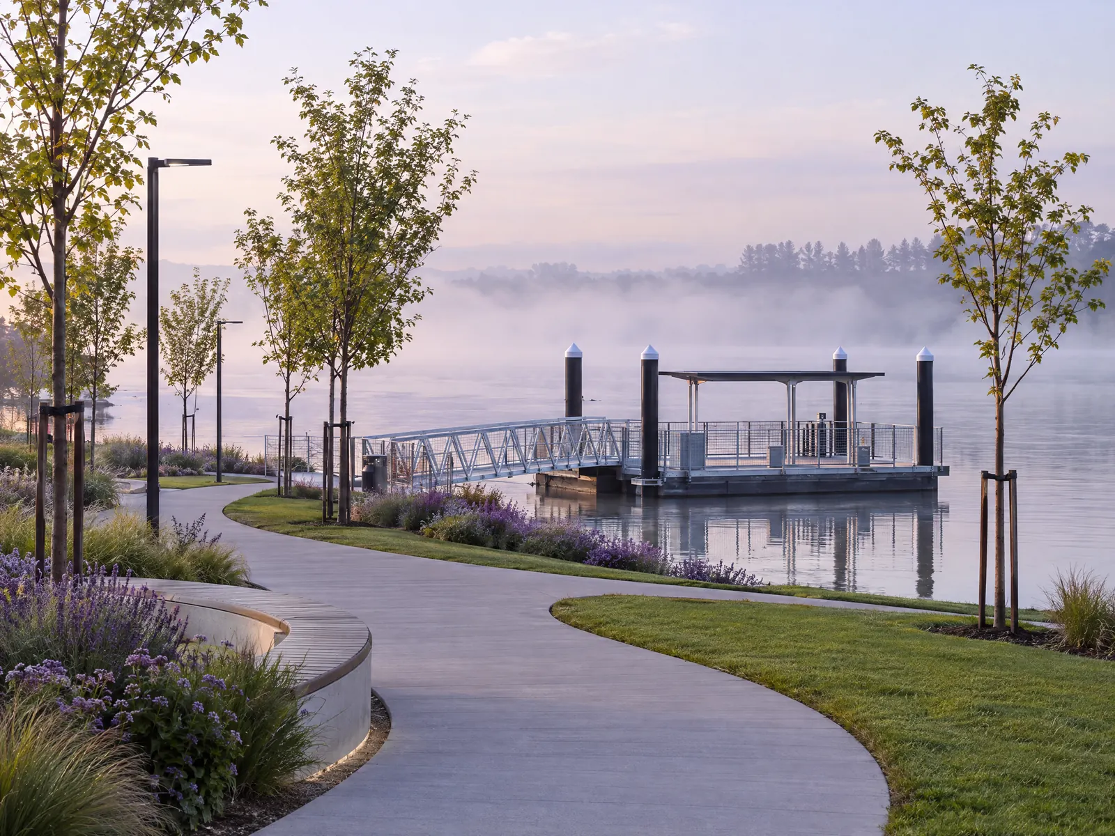Curving park path leading to a small ferry dock on a misty river at morning